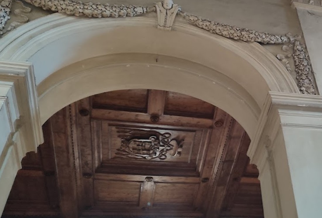 Detail of the basilica’s carved wooden ceiling (1627) and the five-tower coat of arms of Cardinal Ludovico de Torres.